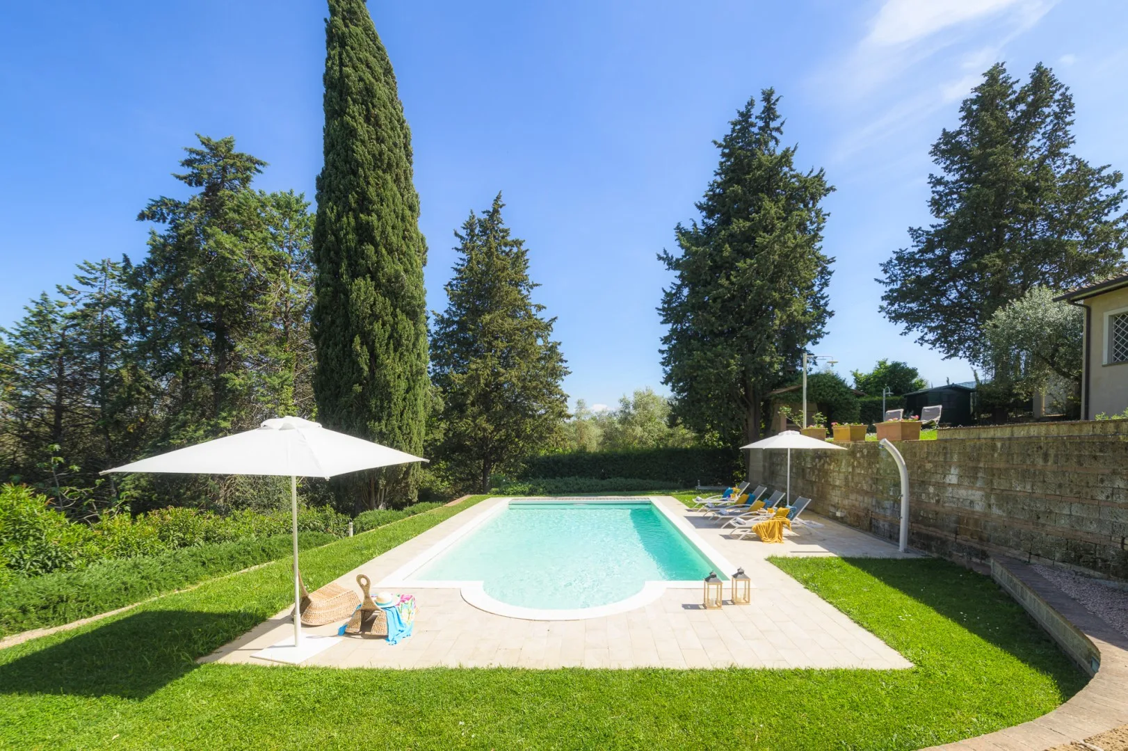 Una piscina al aire libre está en un jardín ajardinado con una sombrilla.