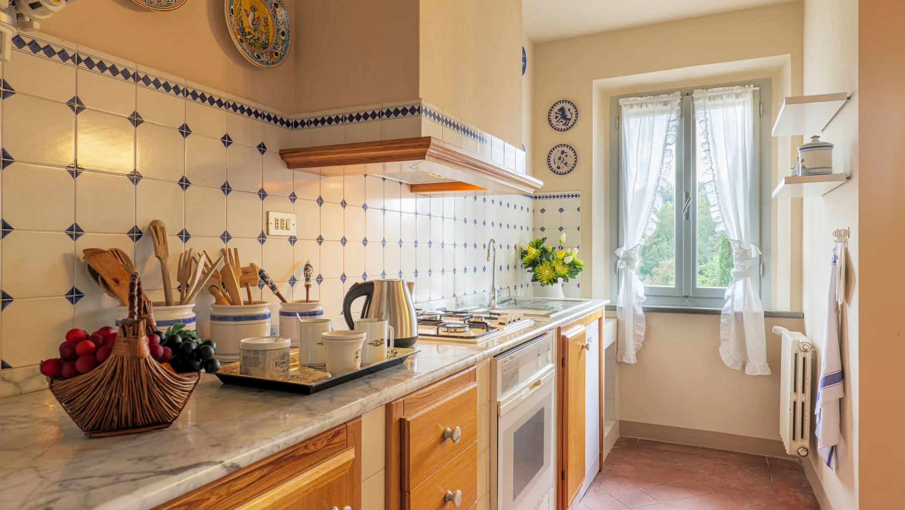 A tiled kitchen with wooden cabinets and a countertop beside a window.