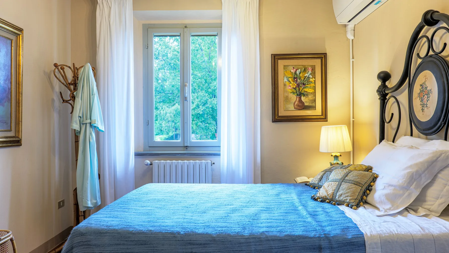 A bedroom with a blue bedspread, a window, and curtains.