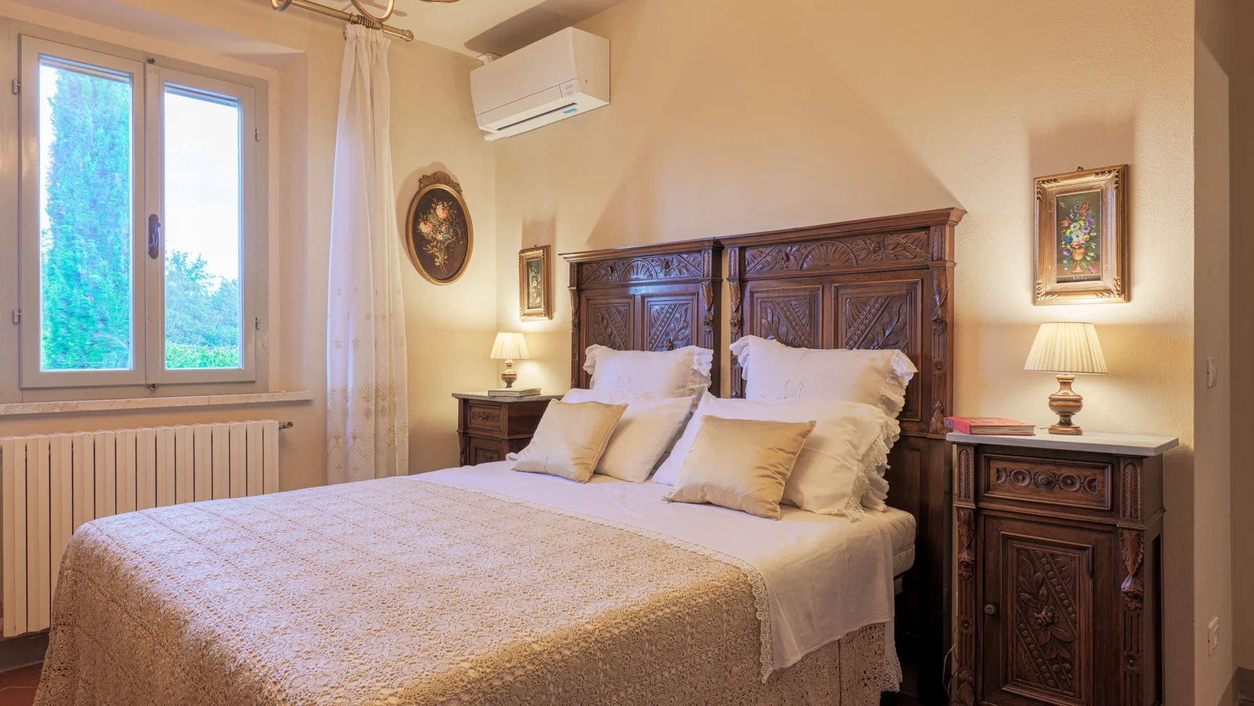 A bedroom with a large bed, carved wooden headboard, and bedside tables.
