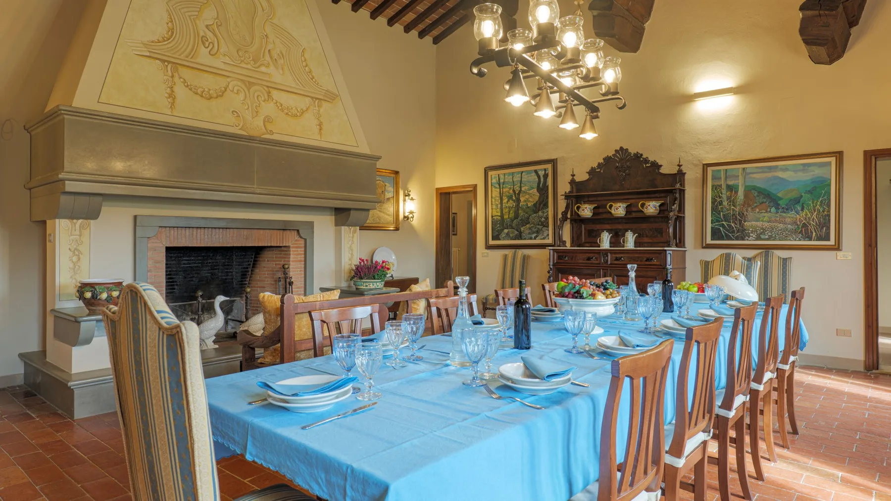 A dining room with a long table set with blue linens and place settings.