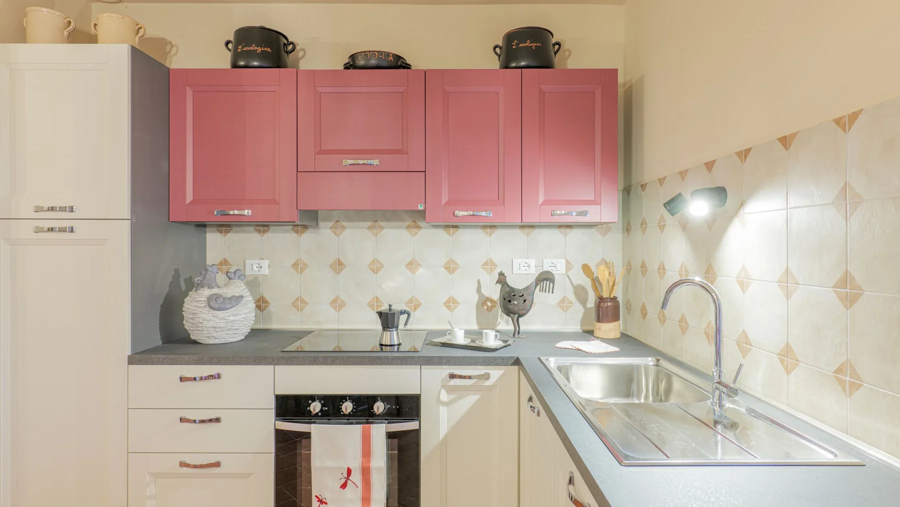 A compact kitchen with pink upper cabinets and a sink along the counter.