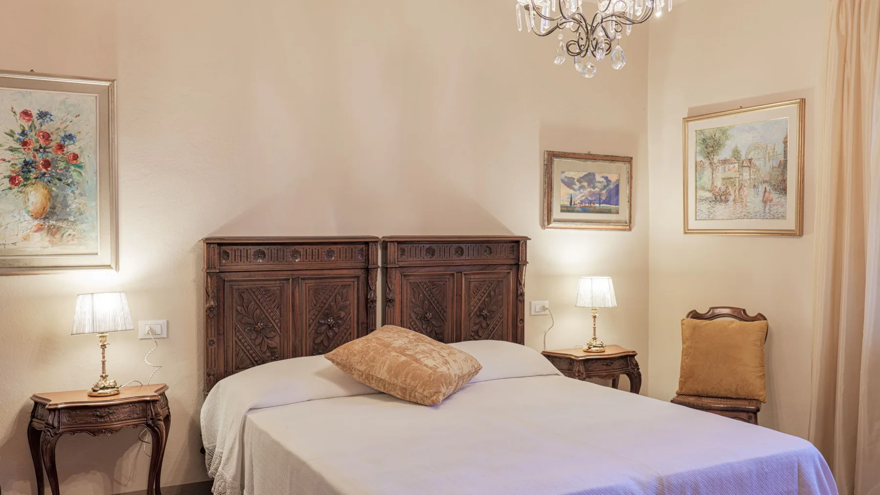 A bedroom with a bed, wooden headboard, and framed artwork on the walls.