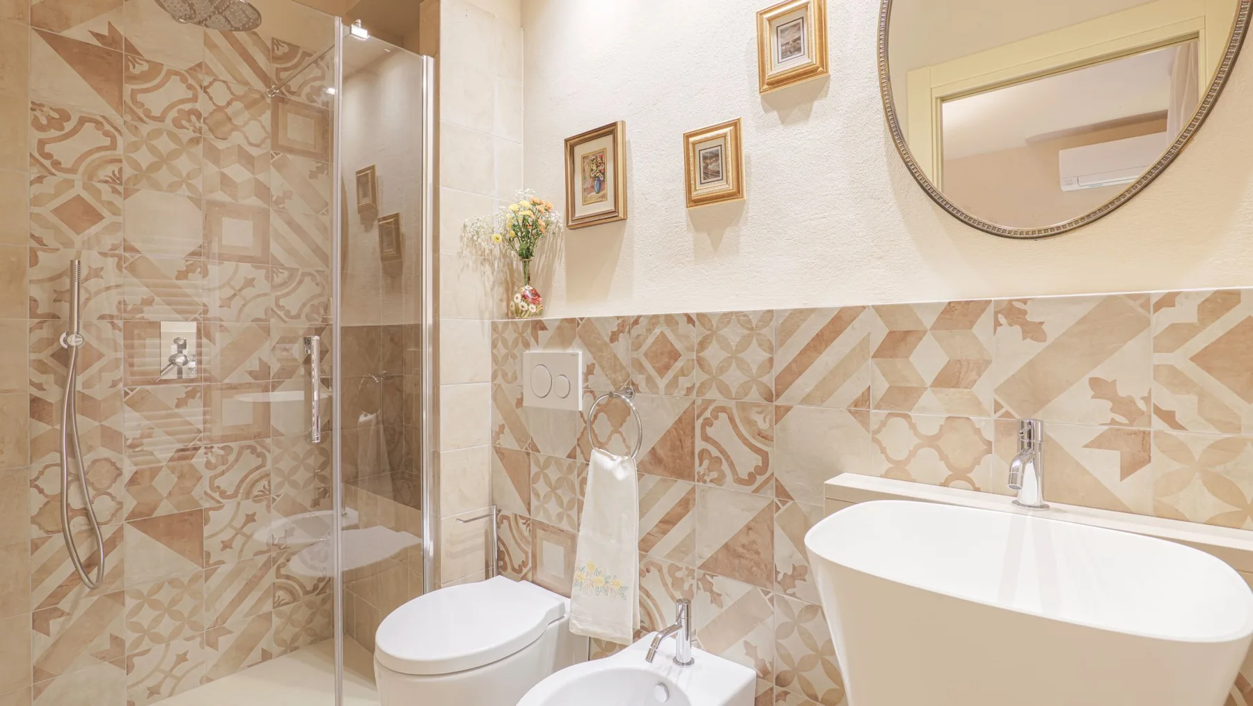 A bathroom with a glass shower, toilet, and bathtub against patterned tile.