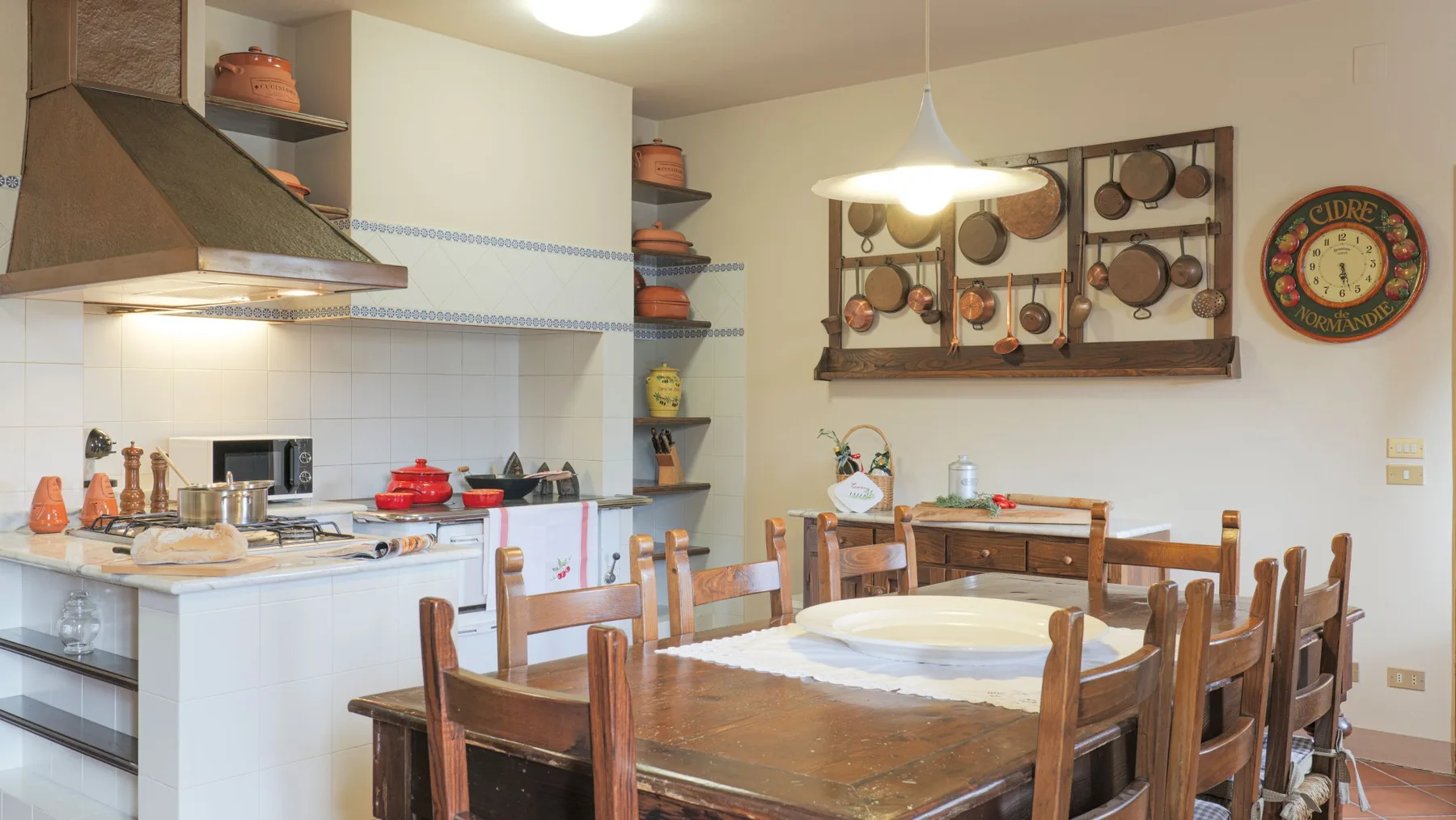 A dining area with a wooden table and kitchen counters behind it.