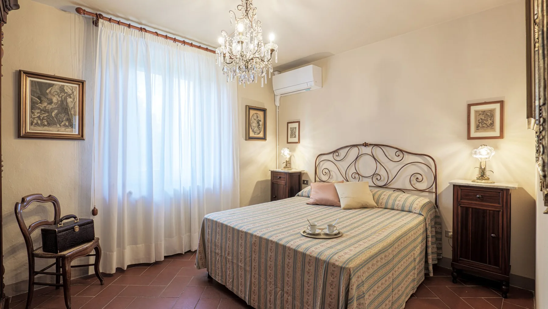 A bedroom with a patterned bed, bedside cabinets, and a chandelier.
