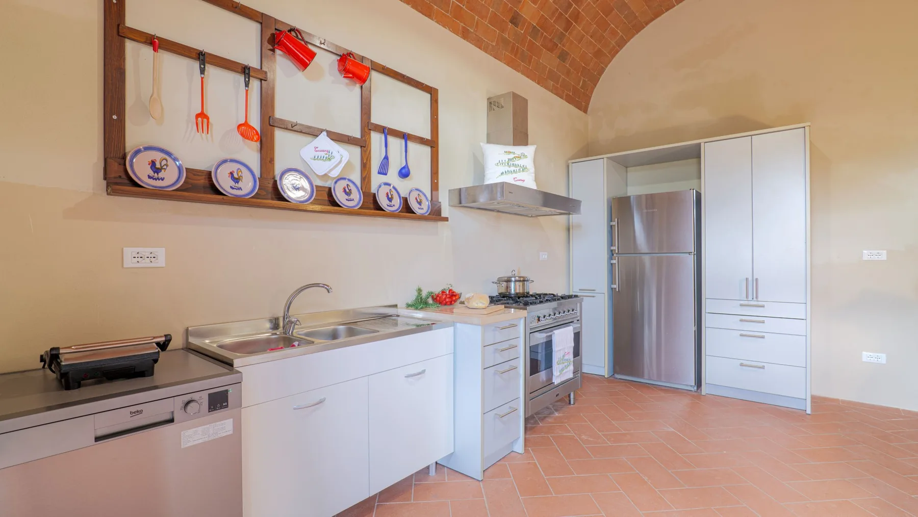 A kitchen with white cabinets, a sink, and a tiled arched ceiling.
