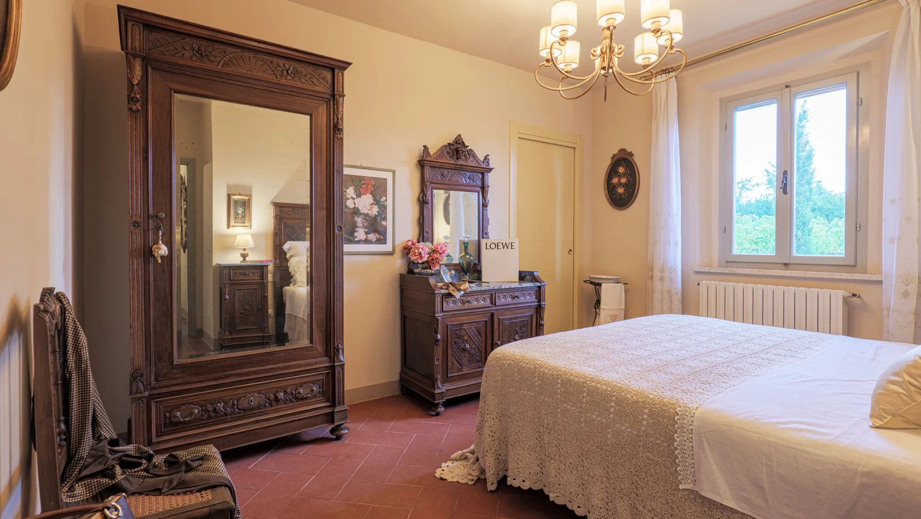 A bedroom with a bed, dark wooden furnishings, and a bright window.