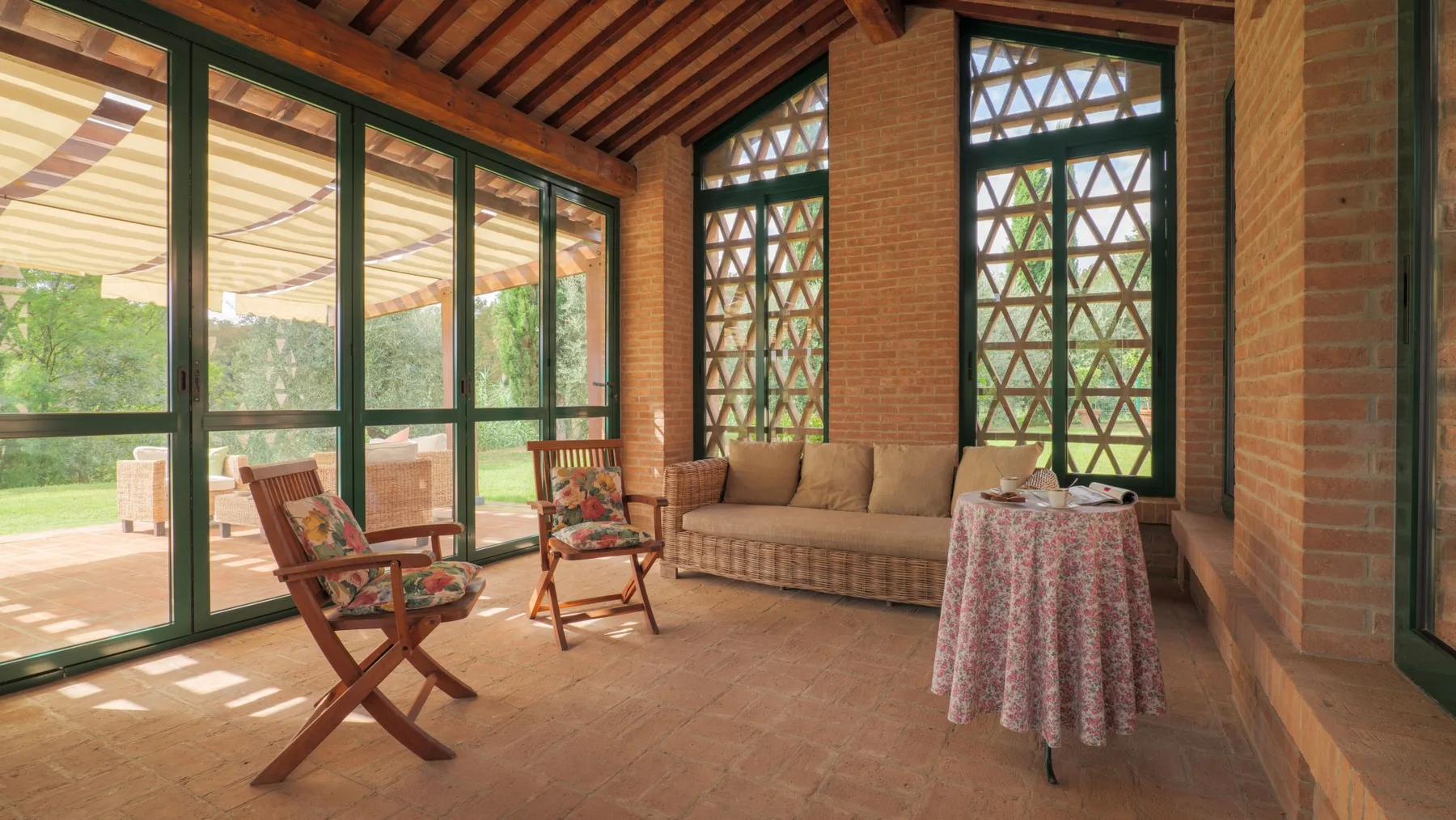 A sunlit sitting area with seating, patterned windows, and glass doors opening onto a patio.
