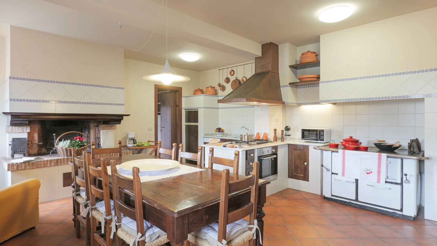A spacious kitchen and dining area with a wooden table and cooking range.