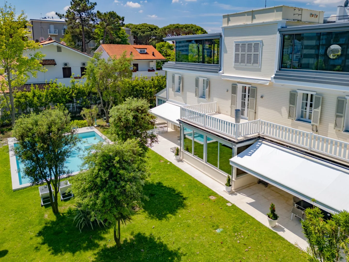 Vista aérea de una casa blanca junto a un jardín y una piscina.