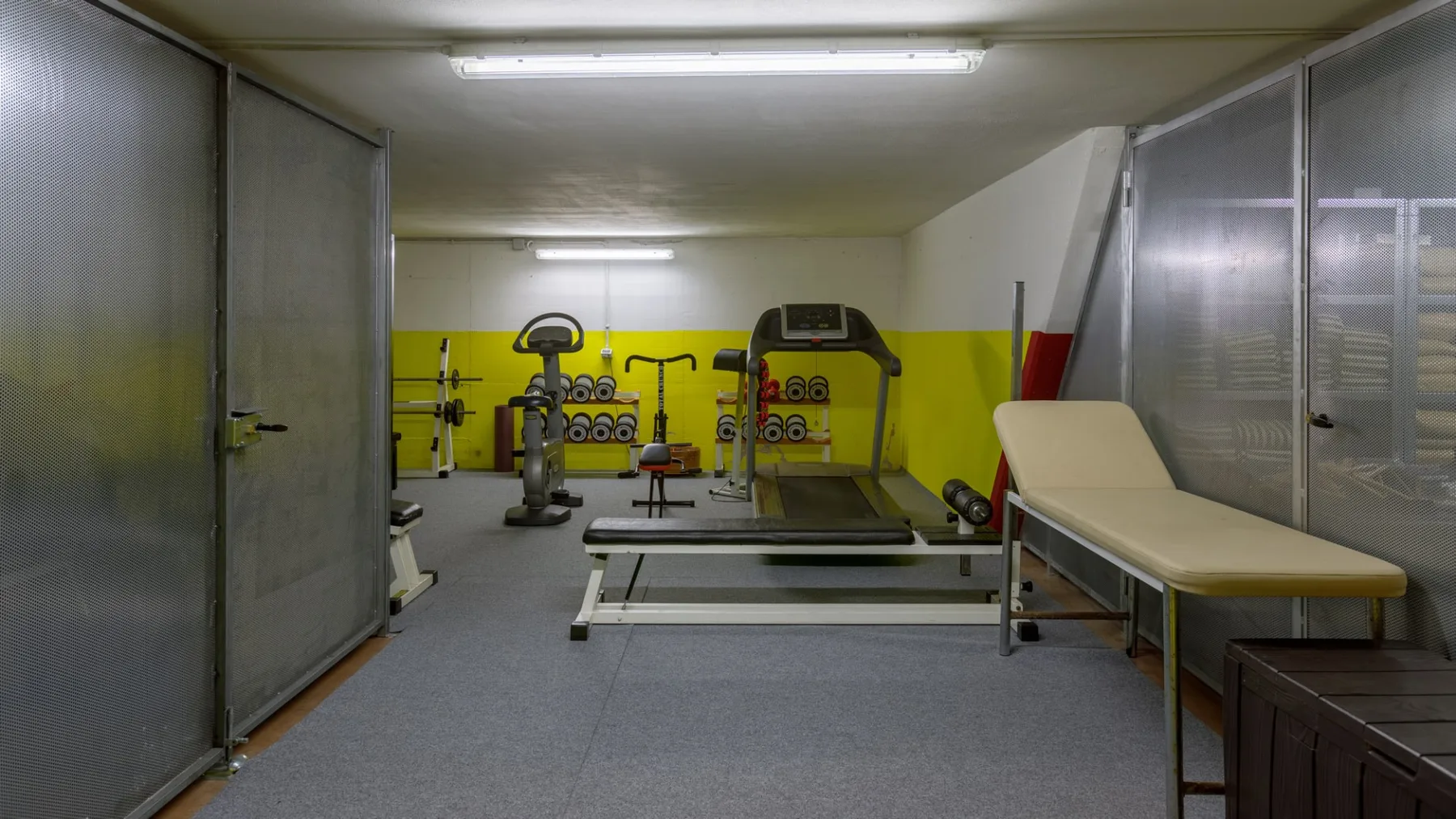 Un gimnasio con máquinas de ejercicio y un banco de pesas.