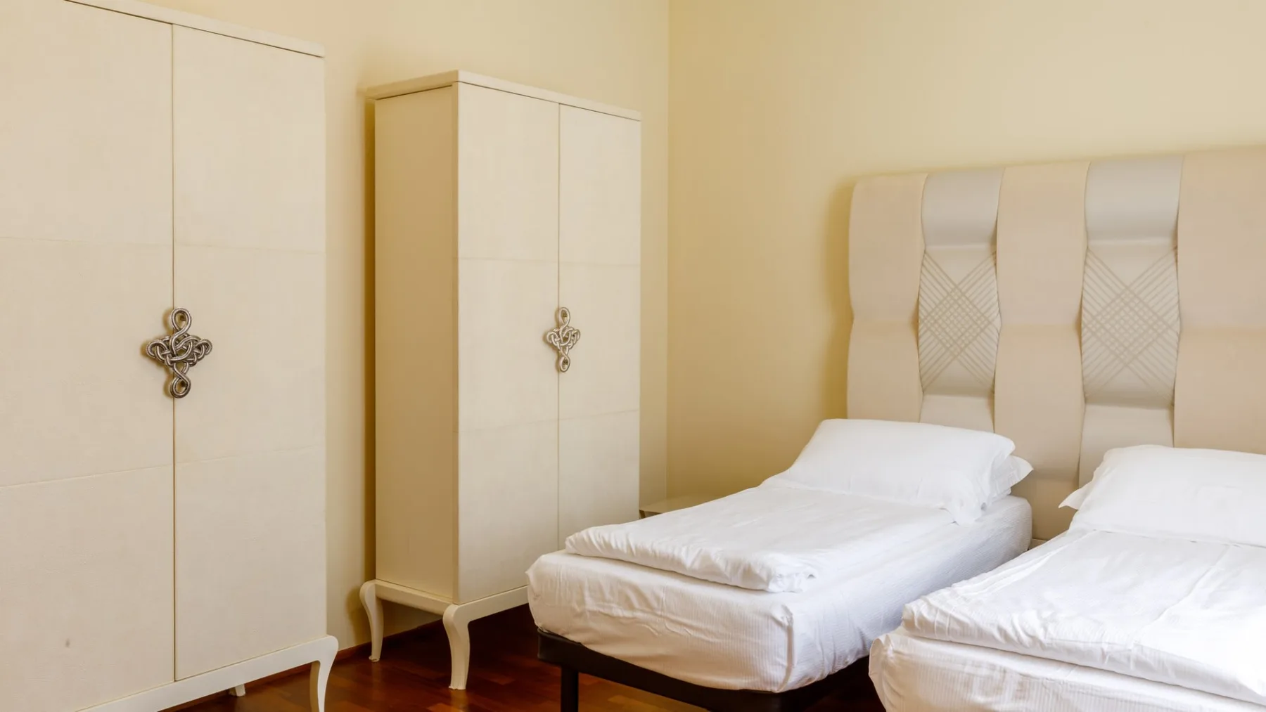Un dormitorio con dos camas individuales y armarios.