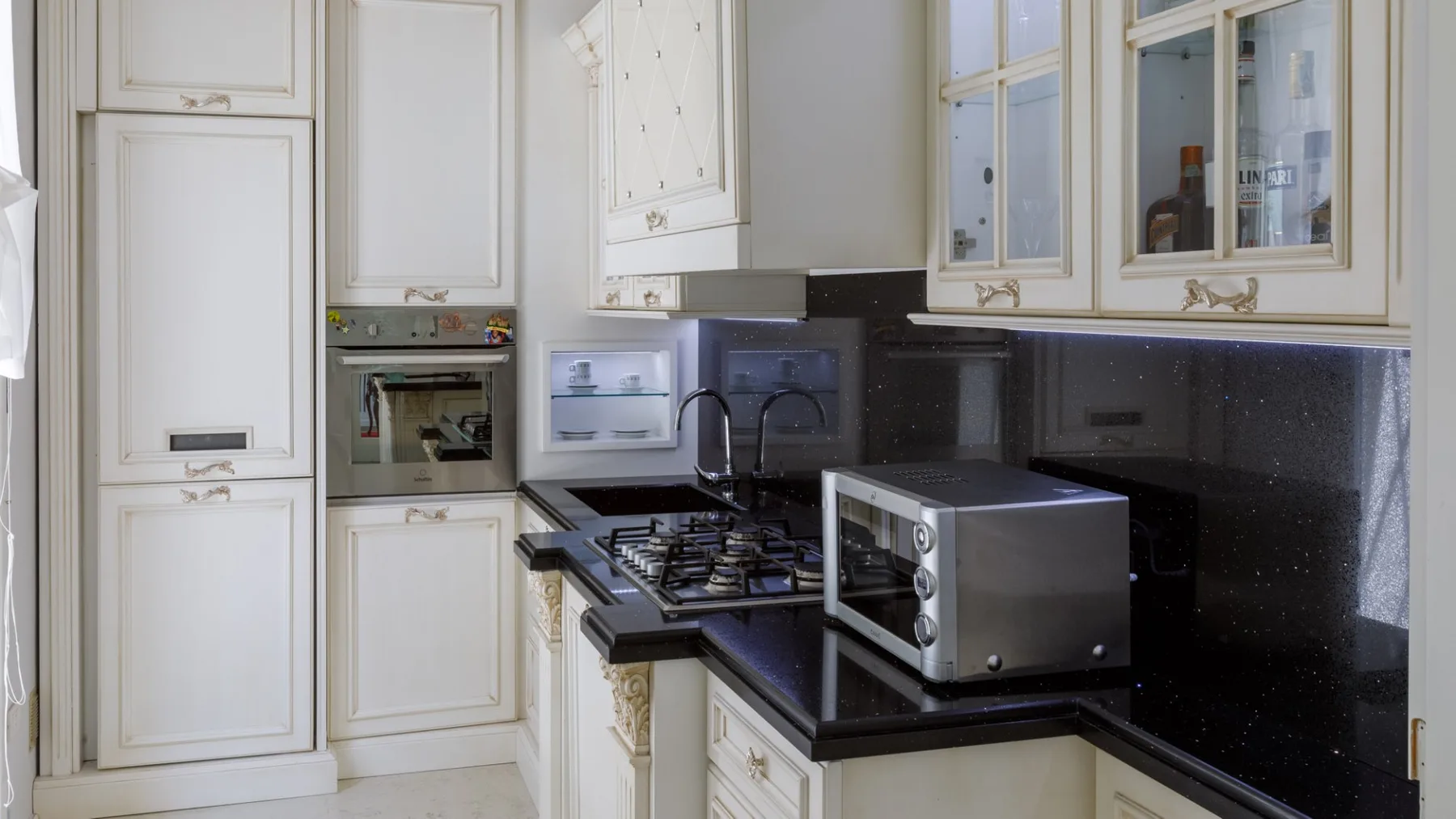 Una cocina luminosa con gabinetes blancos, encimeras oscuras y electrodomésticos de cocina.