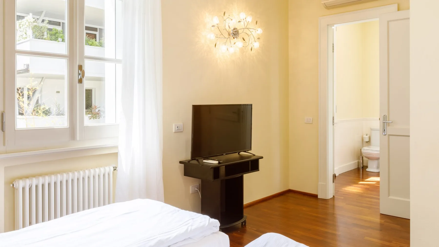 Un dormitorio con un televisor sobre un soporte junto a una puerta abierta.