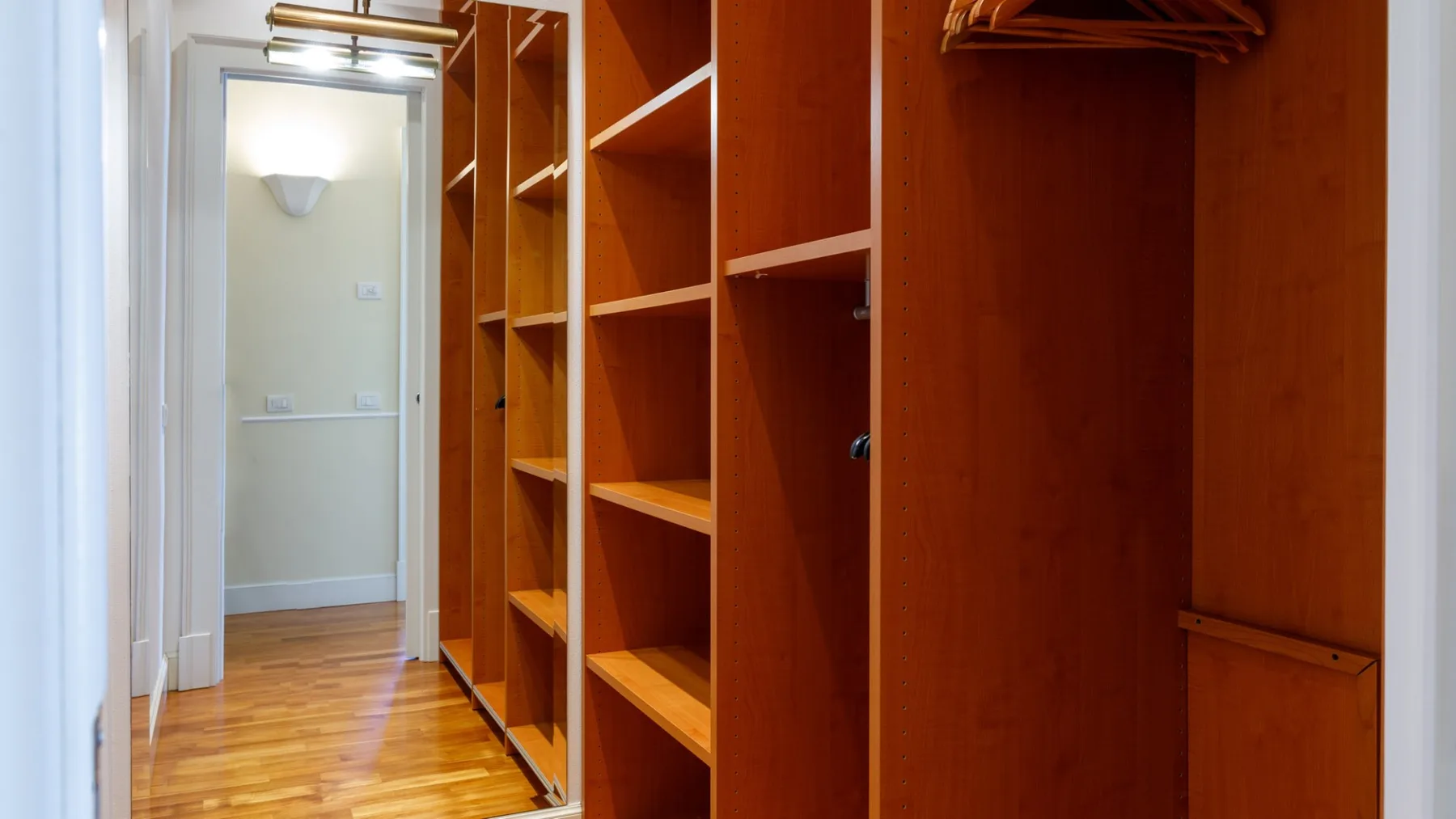 Un vestidor con estantes abiertos de madera y espacio para colgar ropa.
