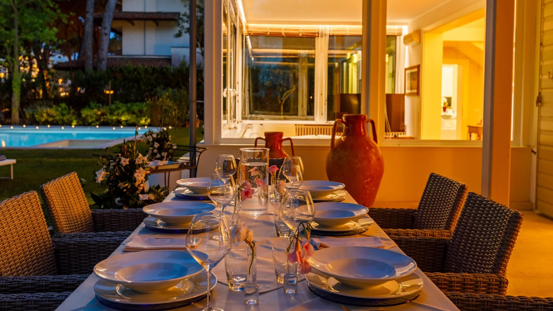 Una mesa está puesta en un patio cubierto junto a una piscina.