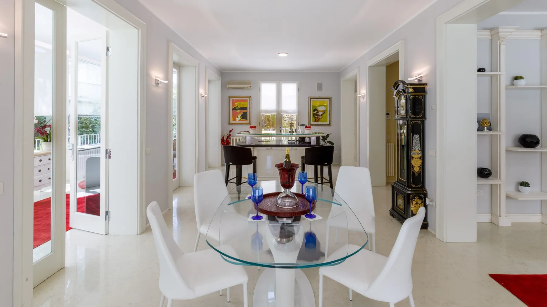 Un comedor luminoso con una mesa de vidrio y asientos blancos.