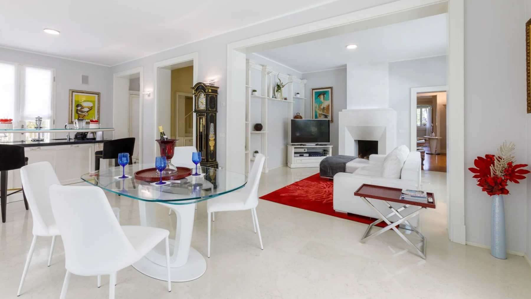 Un luminoso comedor y sala de estar con una mesa de vidrio y asientos blancos.