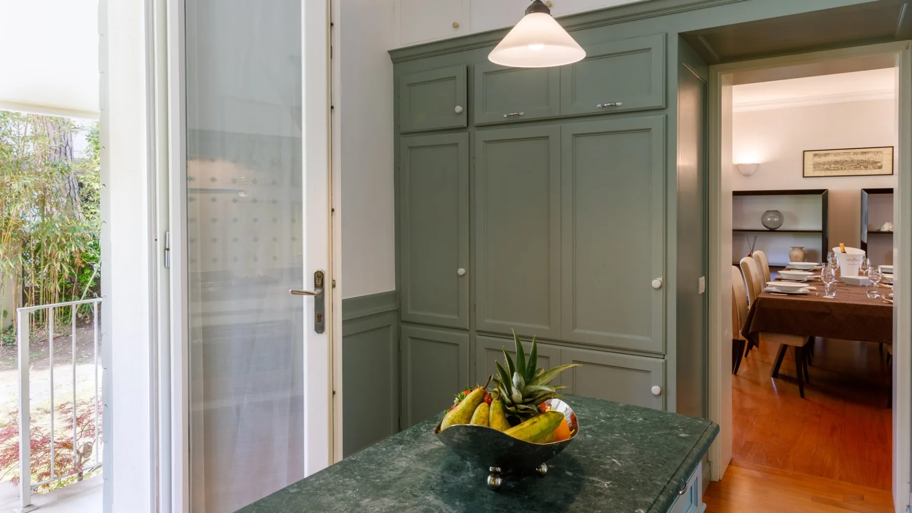 Una cocina con gabinetes verdes y un frutero sobre la encimera.