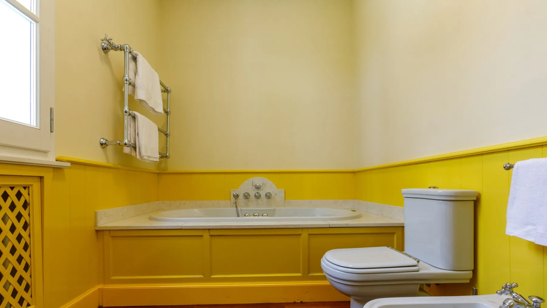 Un baño con bañera, inodoro y paredes de color amarillo brillante.