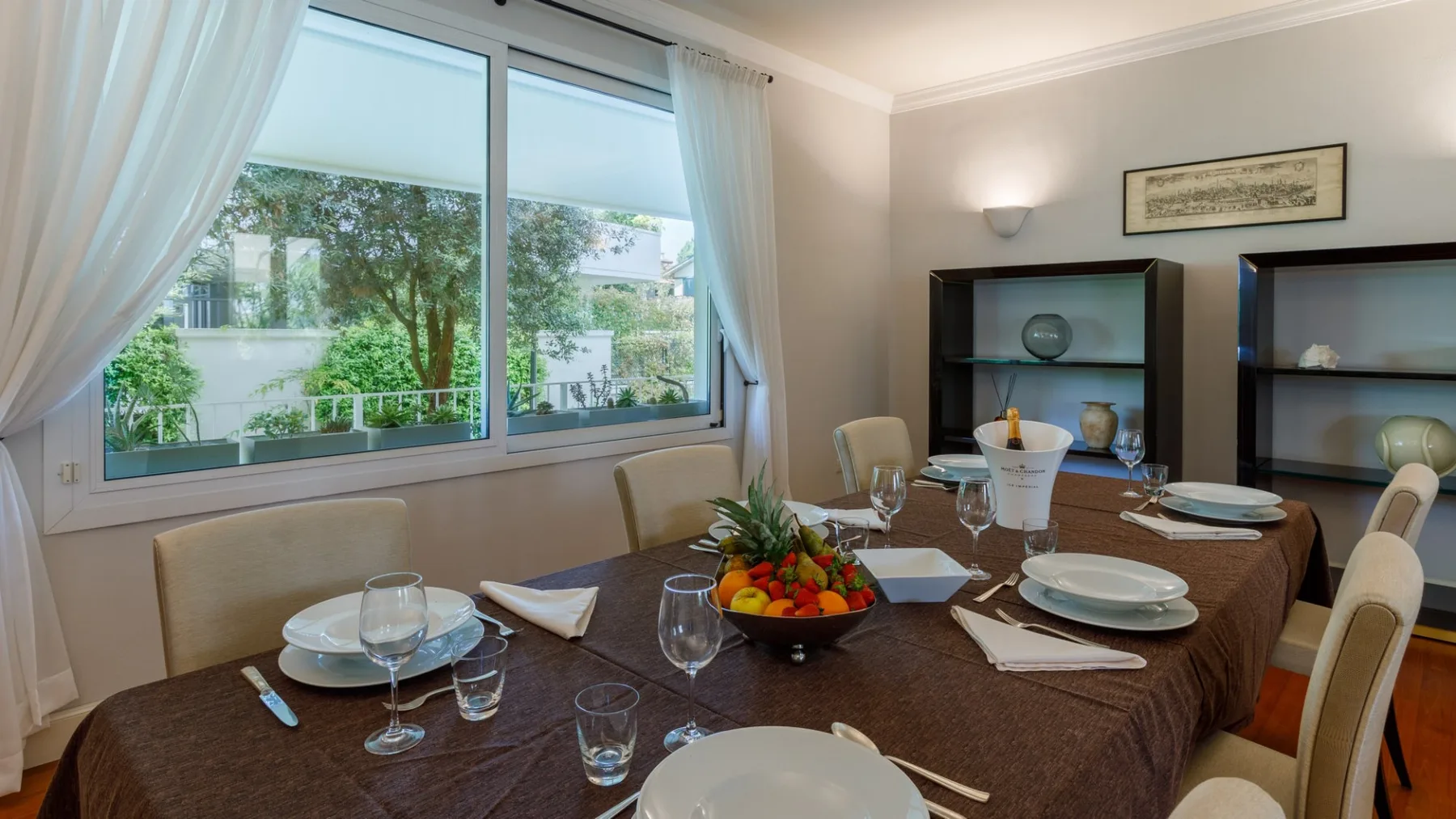 Un comedor con una mesa preparada para comer junto a grandes ventanas.