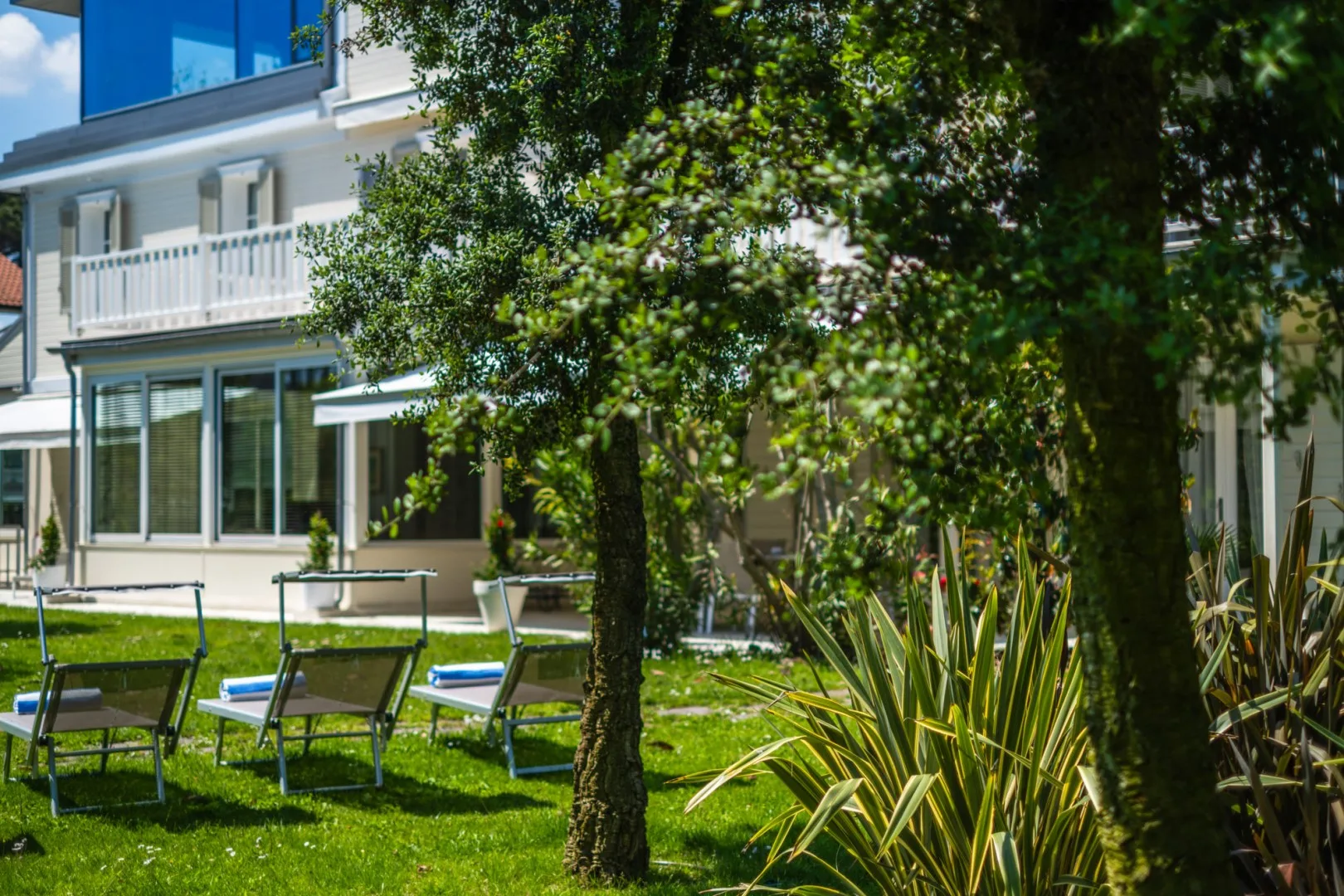 Un césped ajardinado con asientos al aire libre está frente a una casa moderna.