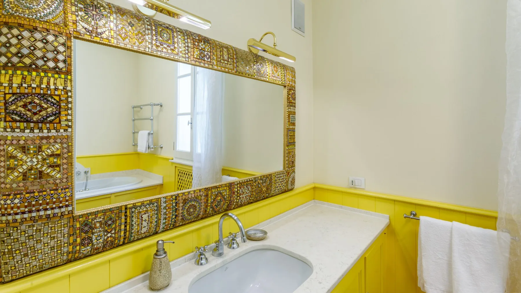 Un tocador de baño con un espejo amplio y una encimera blanca.
