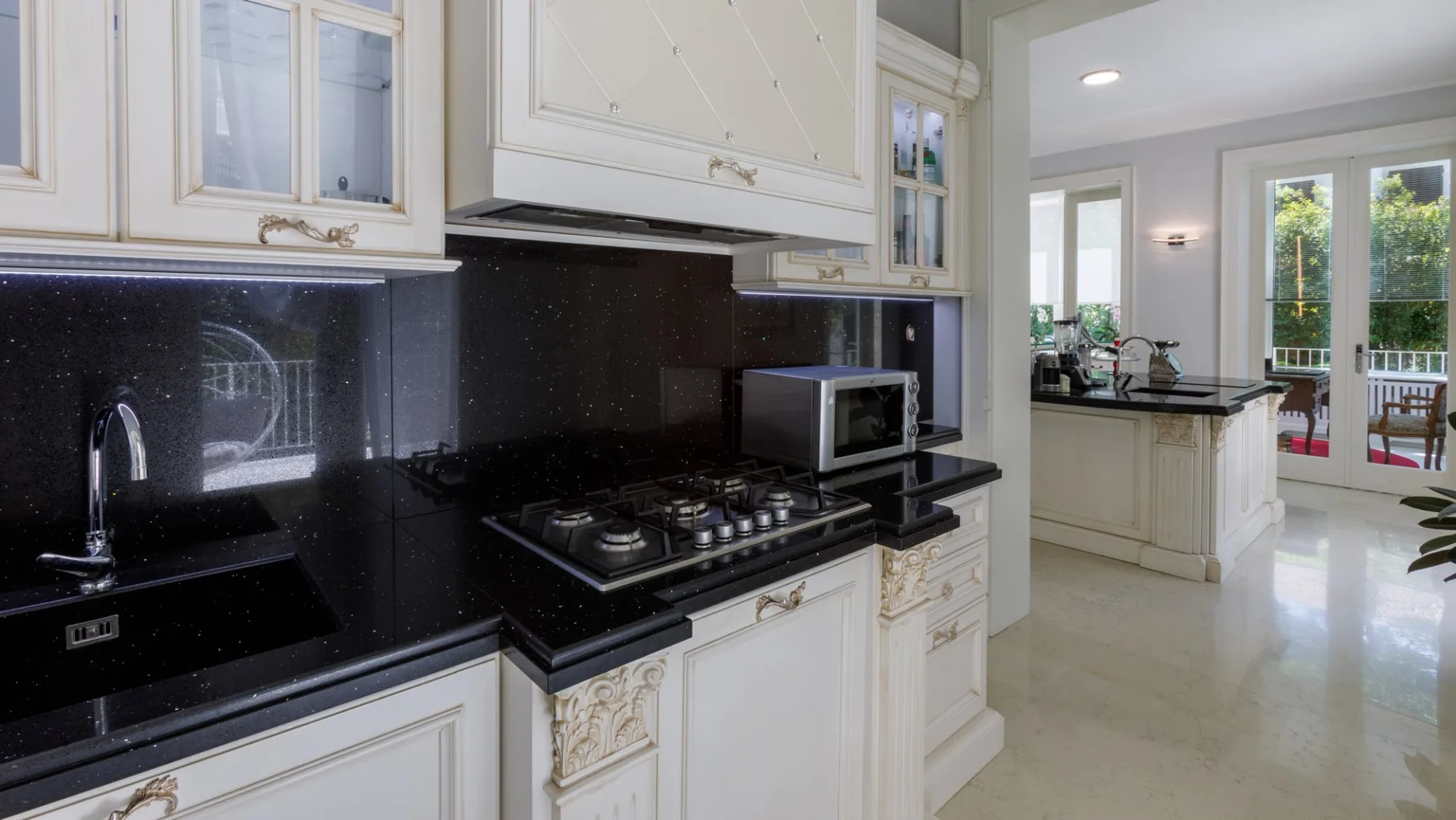 Una cocina luminosa con gabinetes blancos, encimeras oscuras y una estufa.