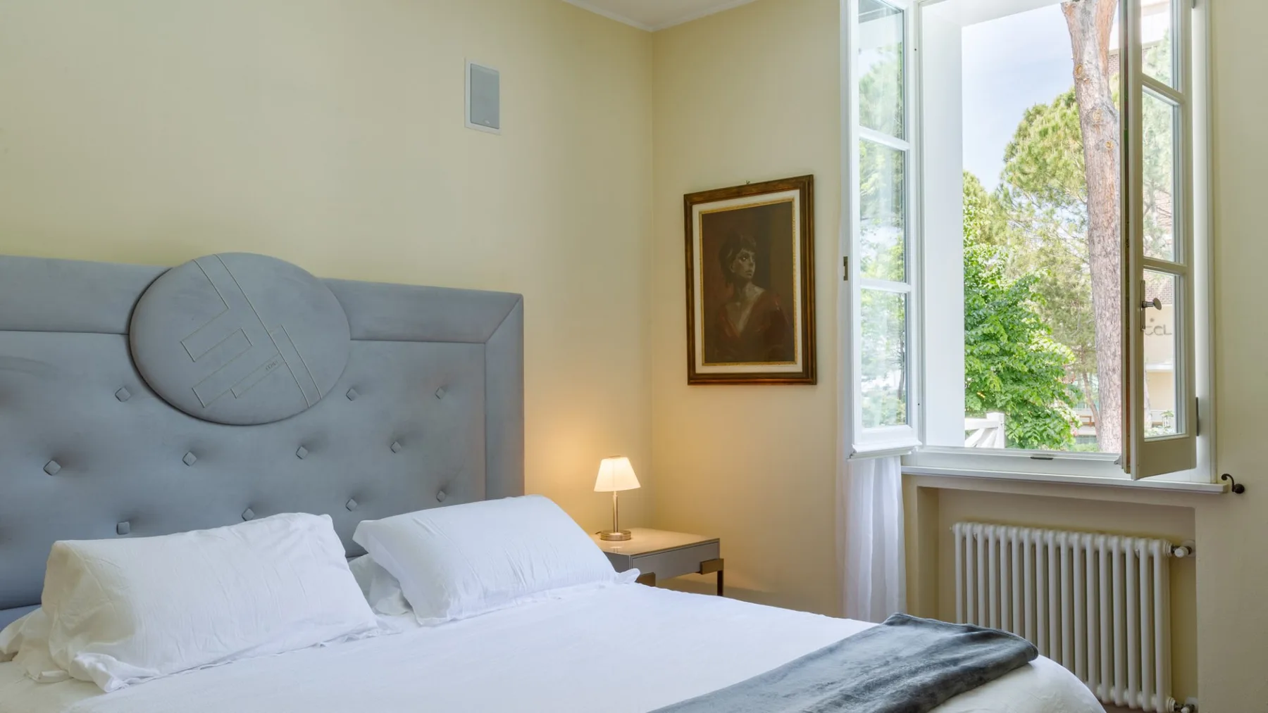 Un dormitorio con una cama junto a una ventana abierta.