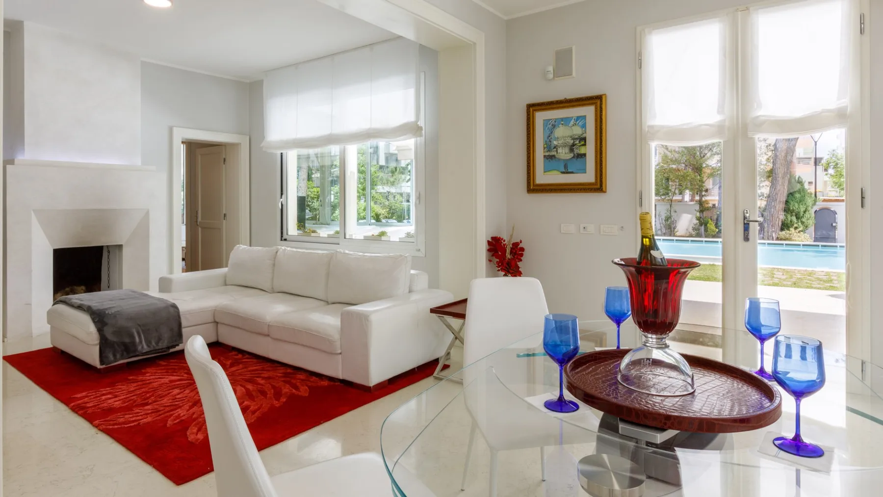 Una luminosa sala de estar con asientos blancos y una mesa de comedor de vidrio.