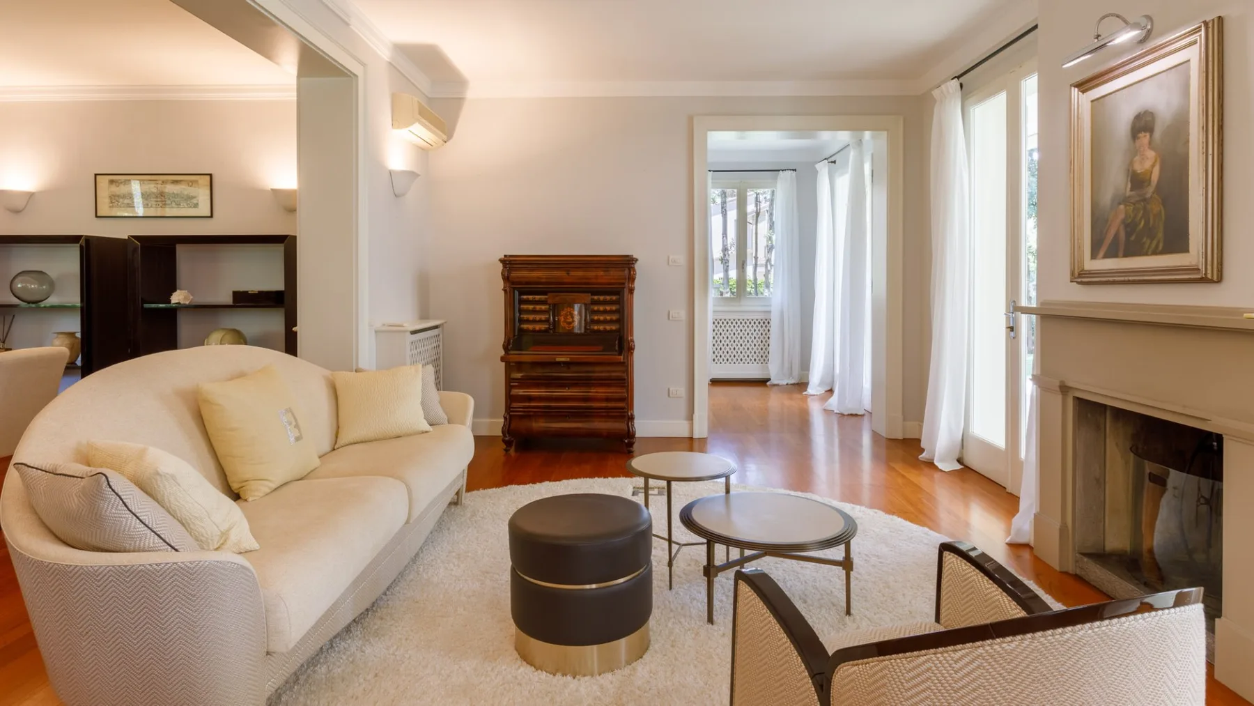Una sala de estar luminosa con asientos color crema, una chimenea y un mueble de madera.