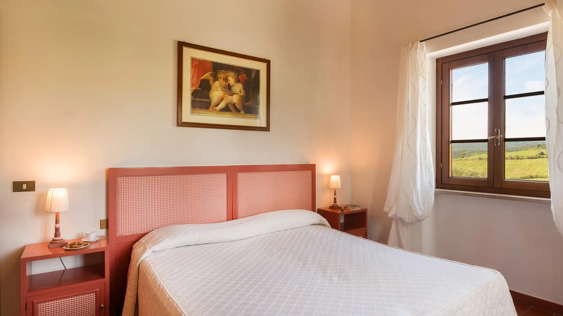 Un dormitorio con una cama bien tendida y una ventana con vista a campos verdes.