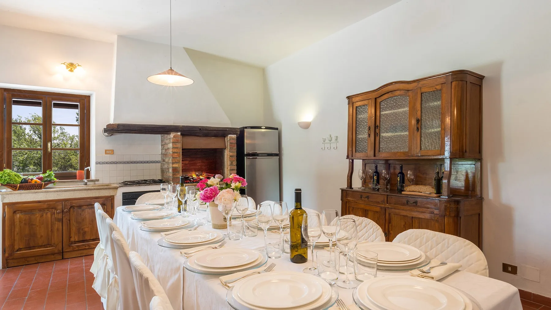 Un comedor con una mesa larga preparada para comer junto a una cocina.