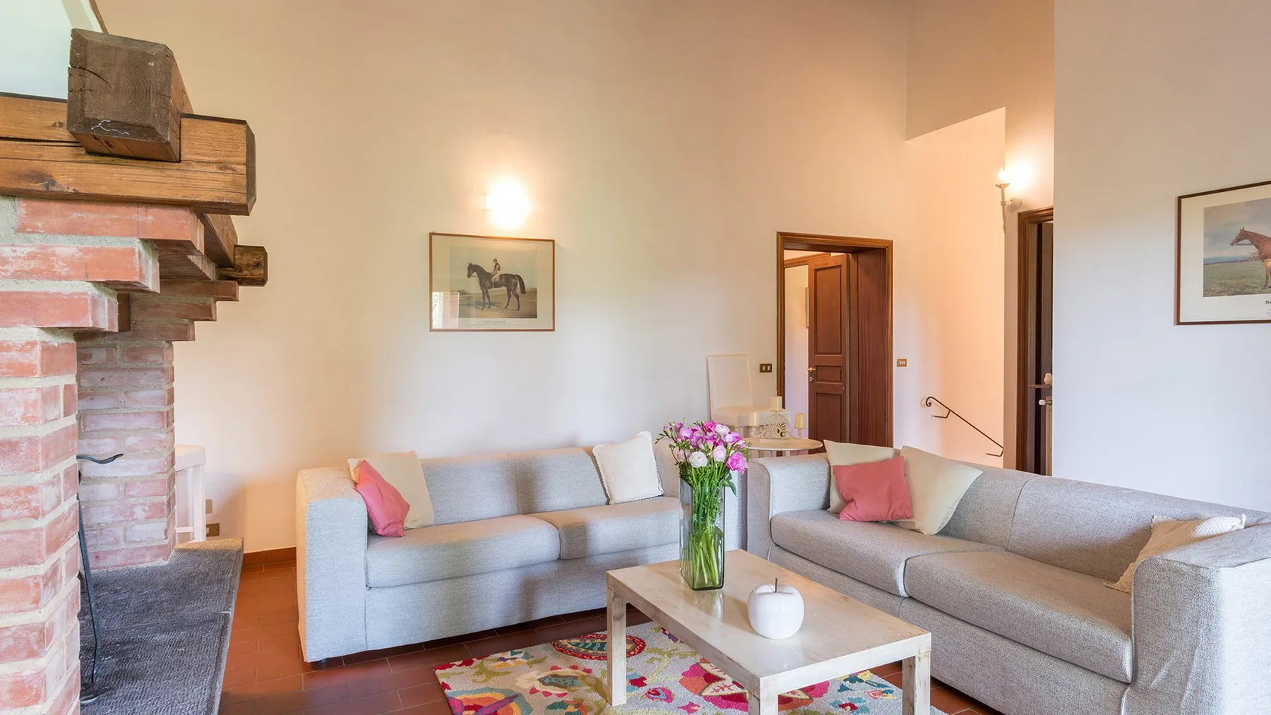 Una sala de estar con dos espacios para sentarse alrededor de una mesa de centro y flores.