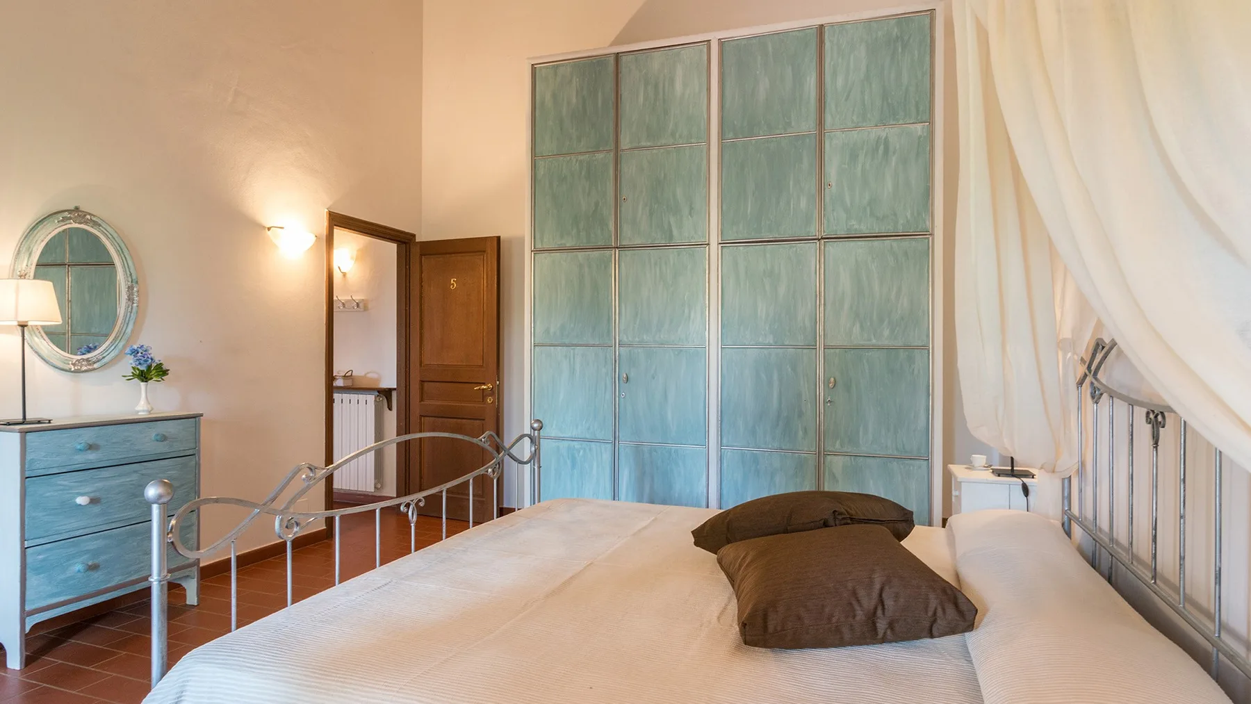Un dormitorio con una cama grande y una pared de paneles azul verdosos.