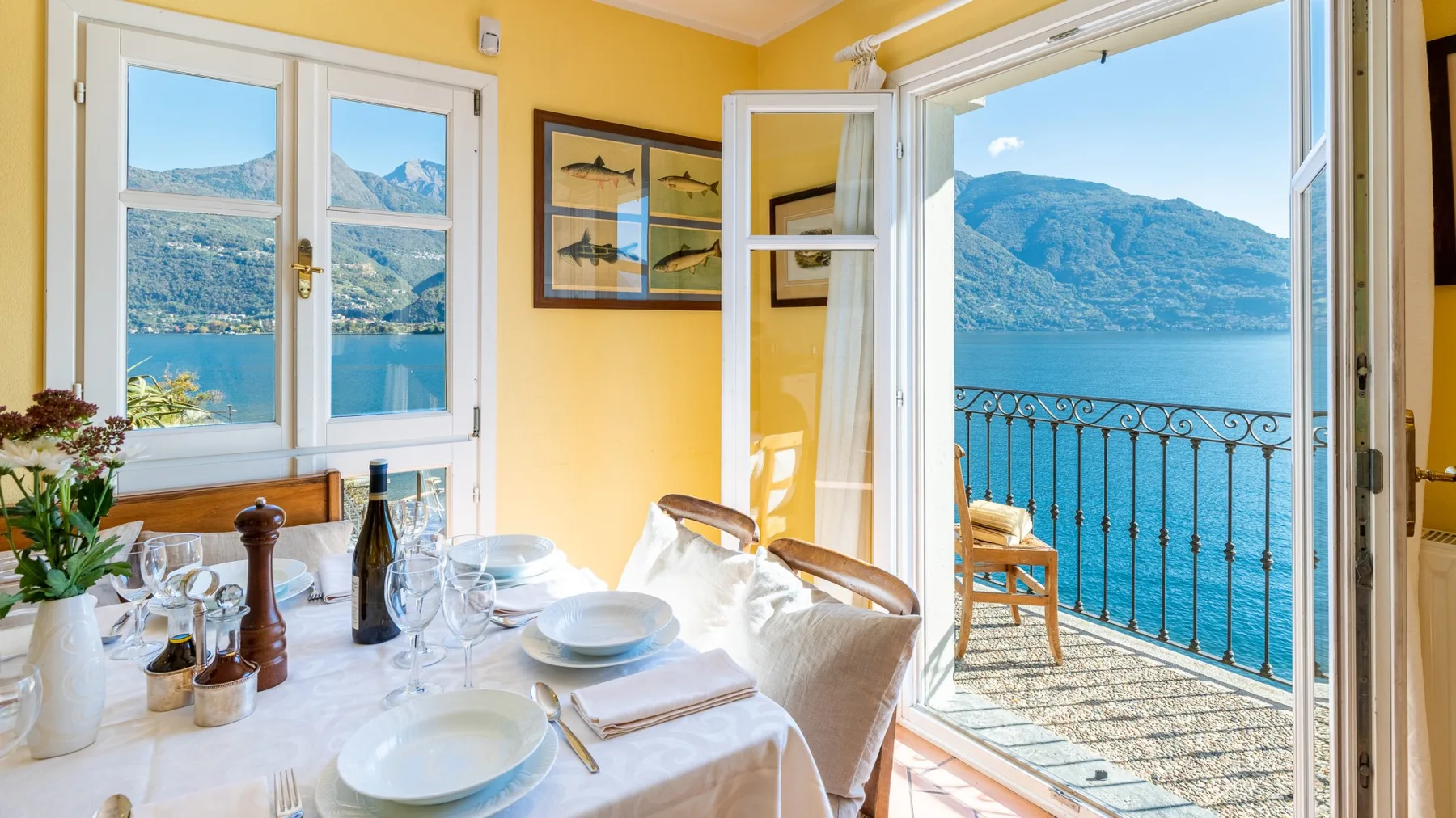 A bright dining area opens onto a balcony overlooking the lake and mountains.