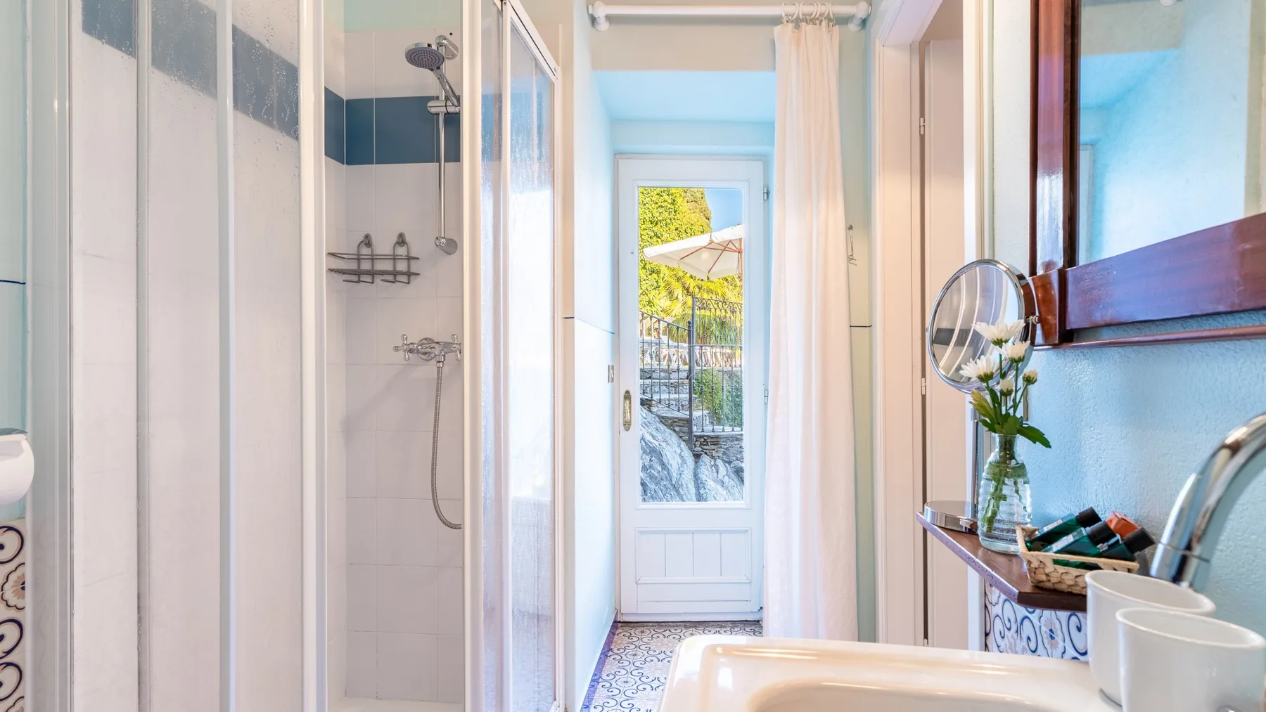 A bright bathroom with a shower and a glazed door opening onto a small balcony.