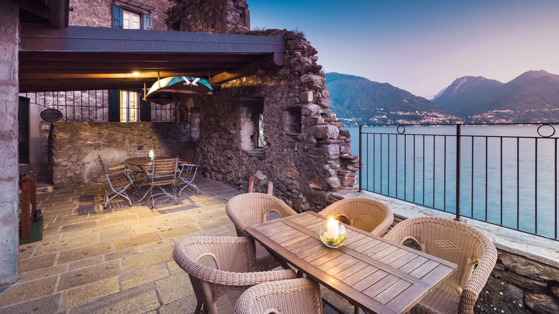 A stone terrace dining area overlooks a lake and the surrounding mountains.