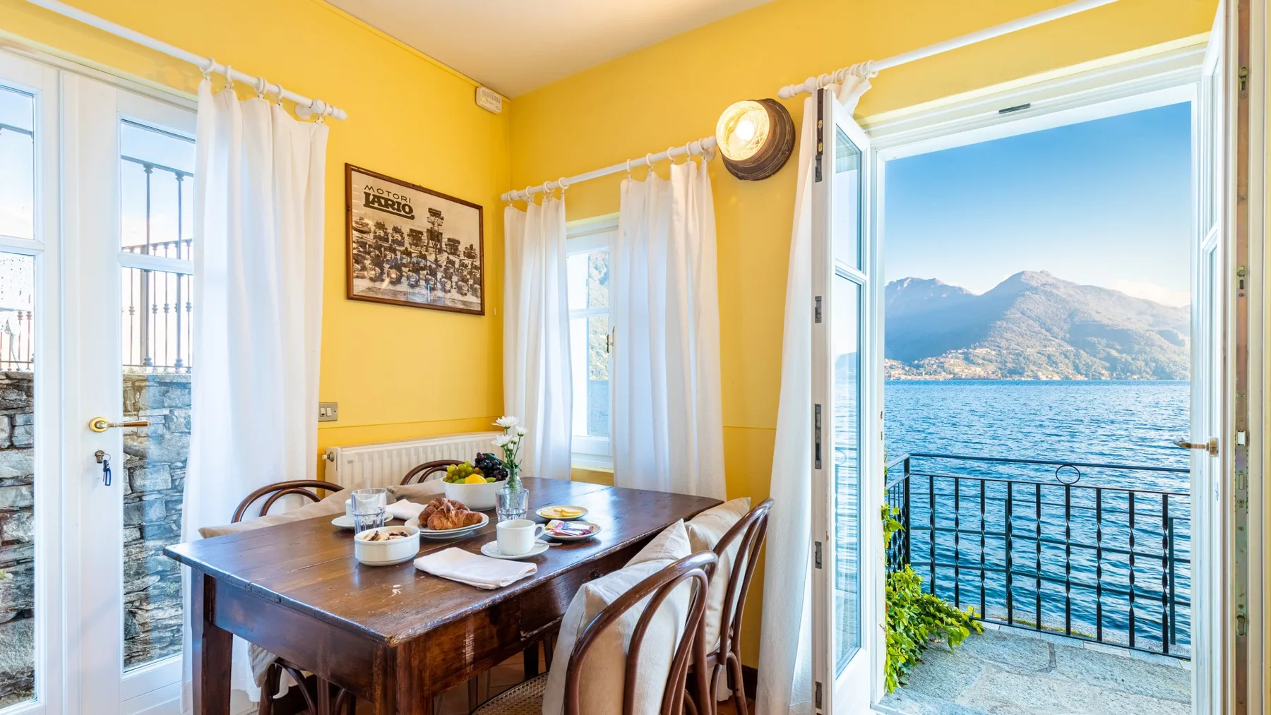 A dining area with a wooden table beside open doors overlooking the water.