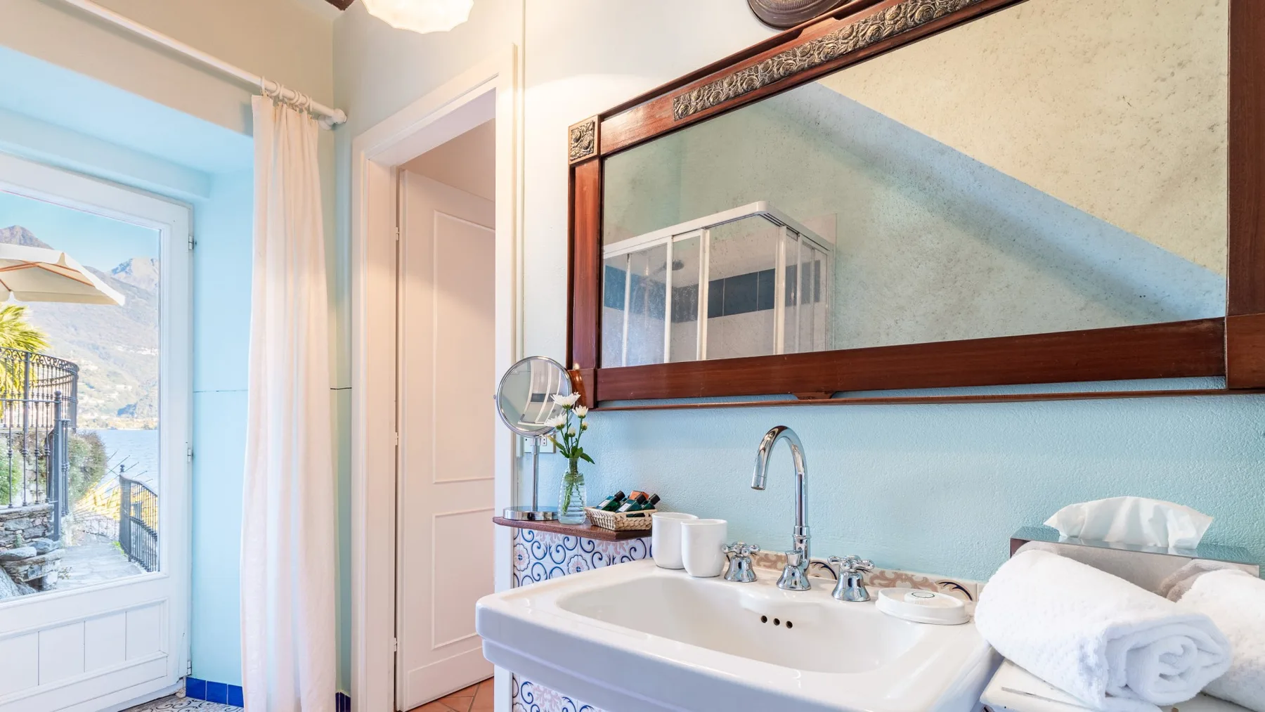 A bathroom vanity with a wide mirror and a large window.
