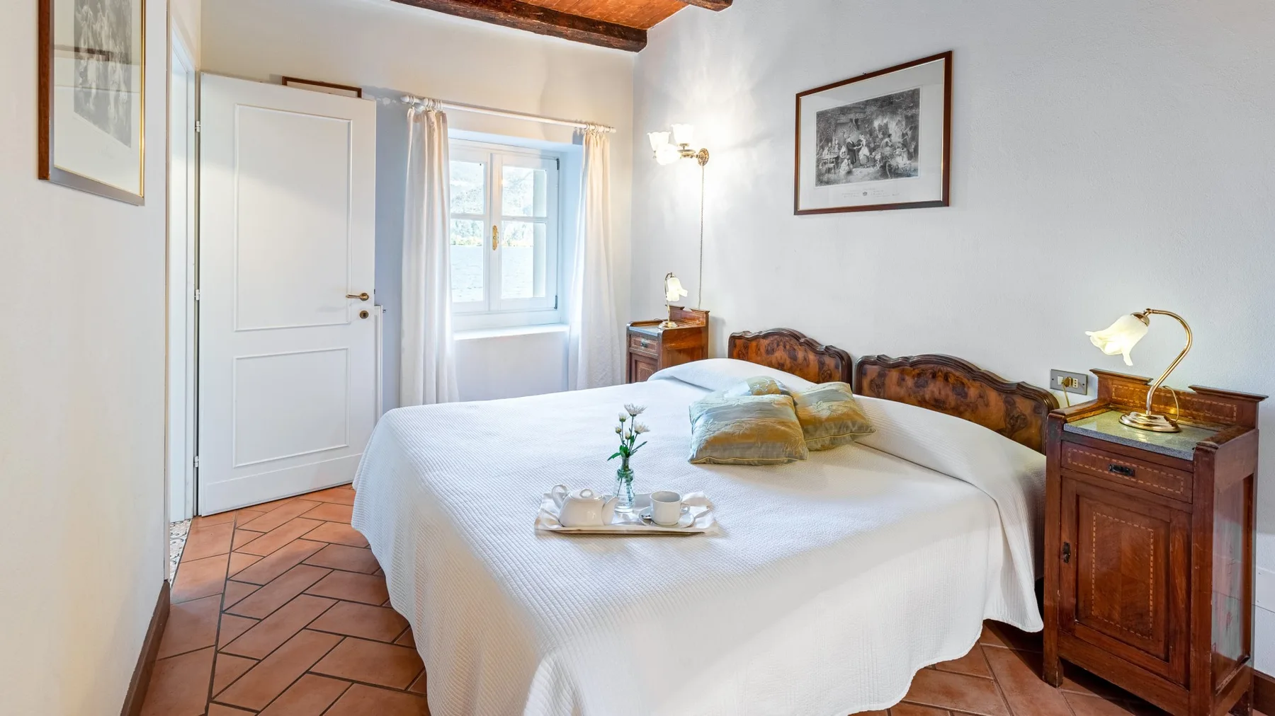 A bedroom with a large bed, bedside tables, and a window.