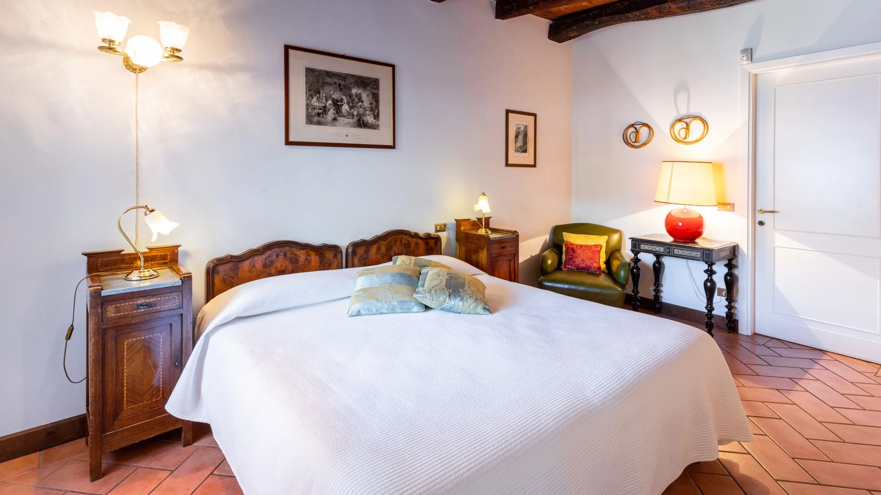A bedroom with a large bed, wooden bedside furniture, and a chair.