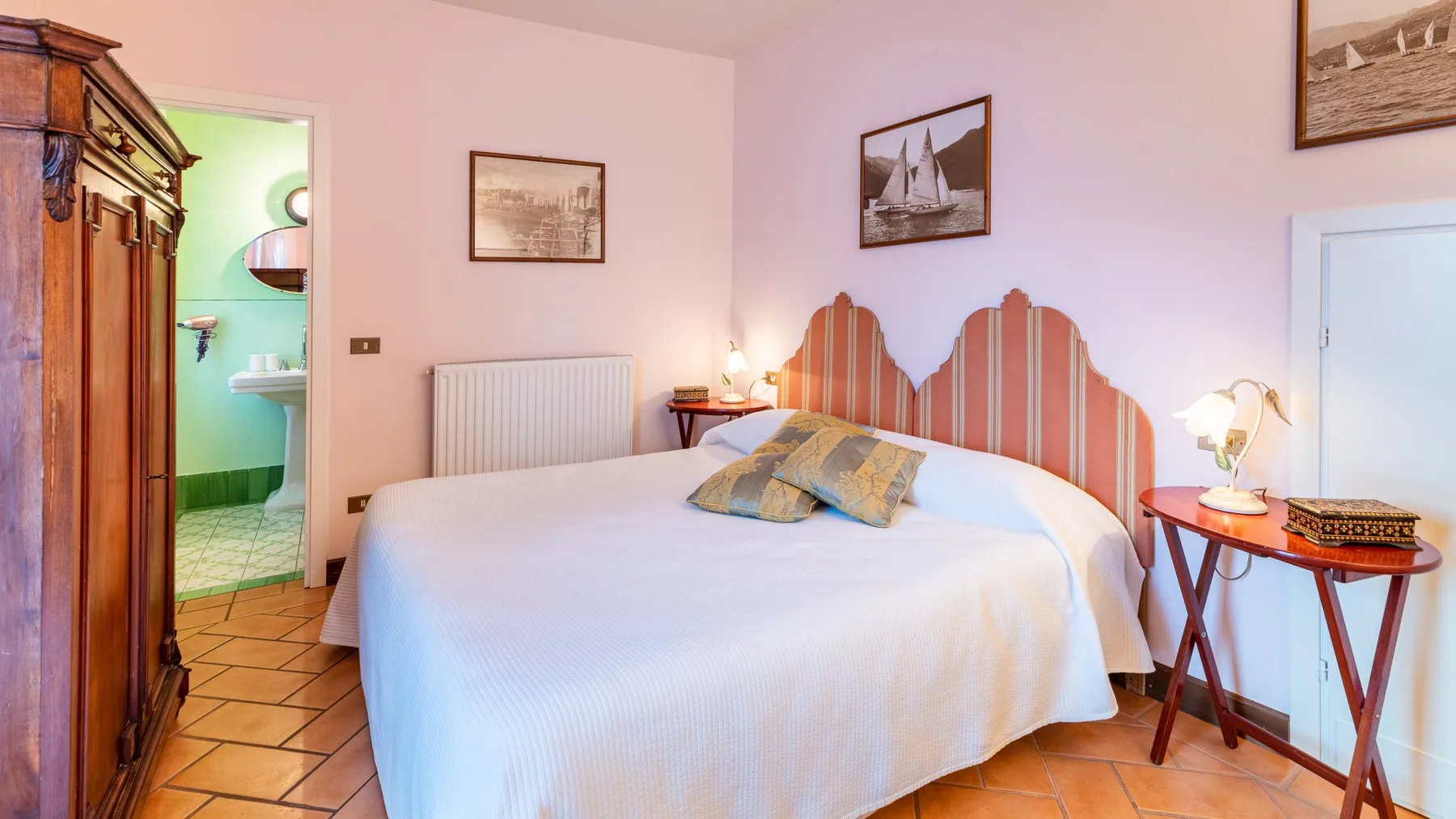 A bedroom with a large bed, striped headboard, and wooden floor.