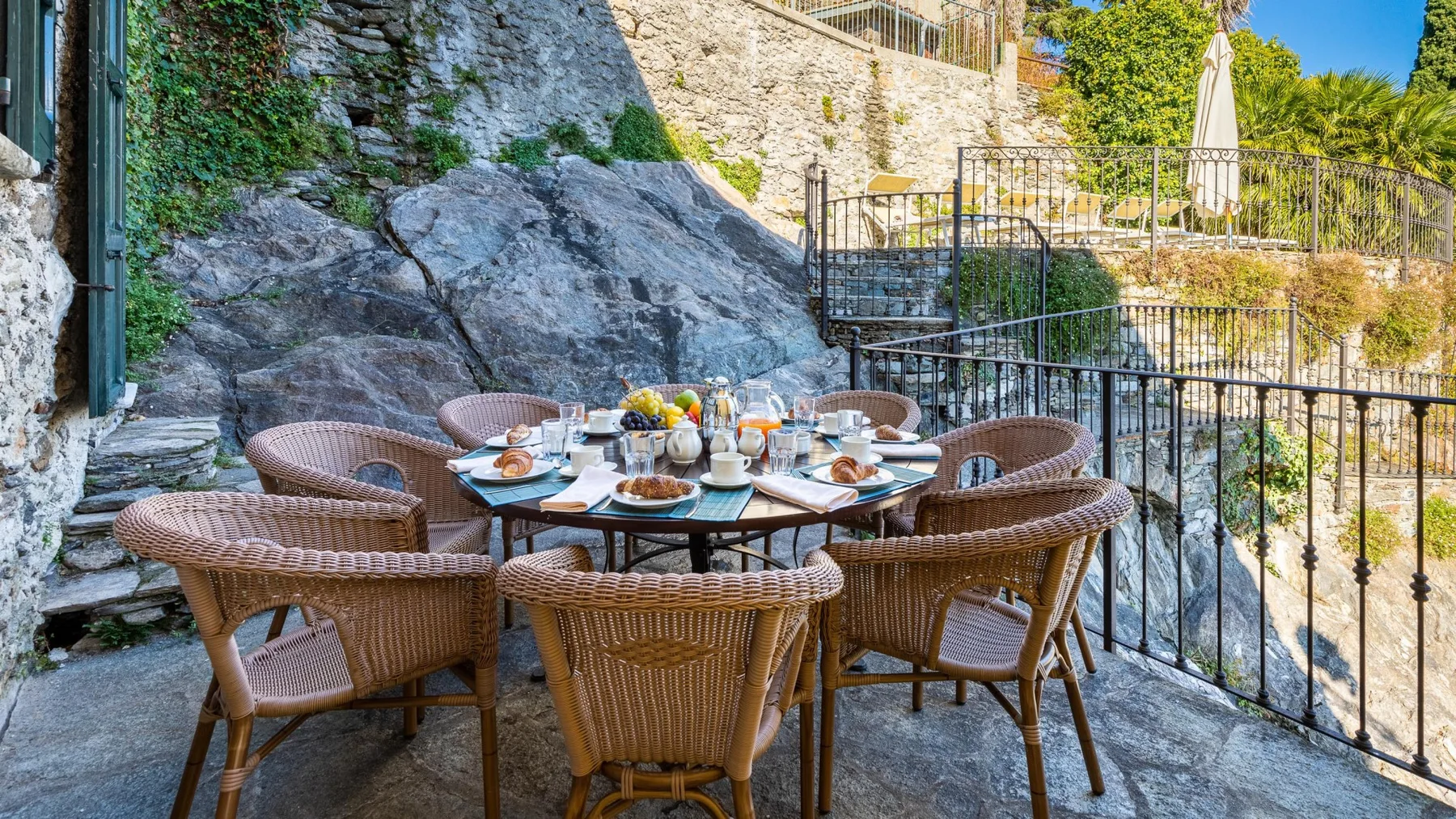 An outdoor dining area with wicker seating and a table set for a meal.