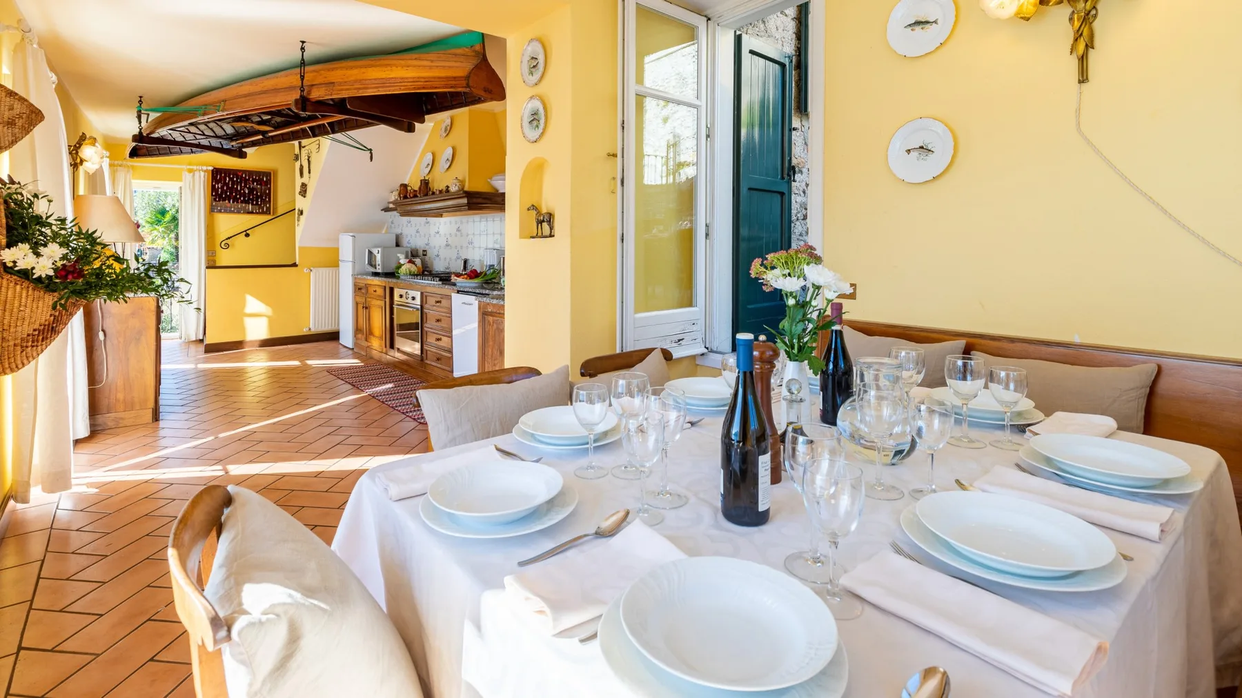 A dining area with a set table beside a bright kitchen.