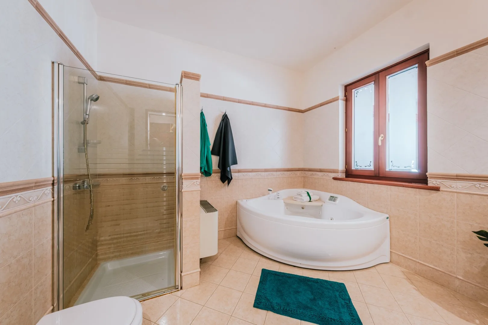 A bathroom with a corner shower, a bathtub, and a window.