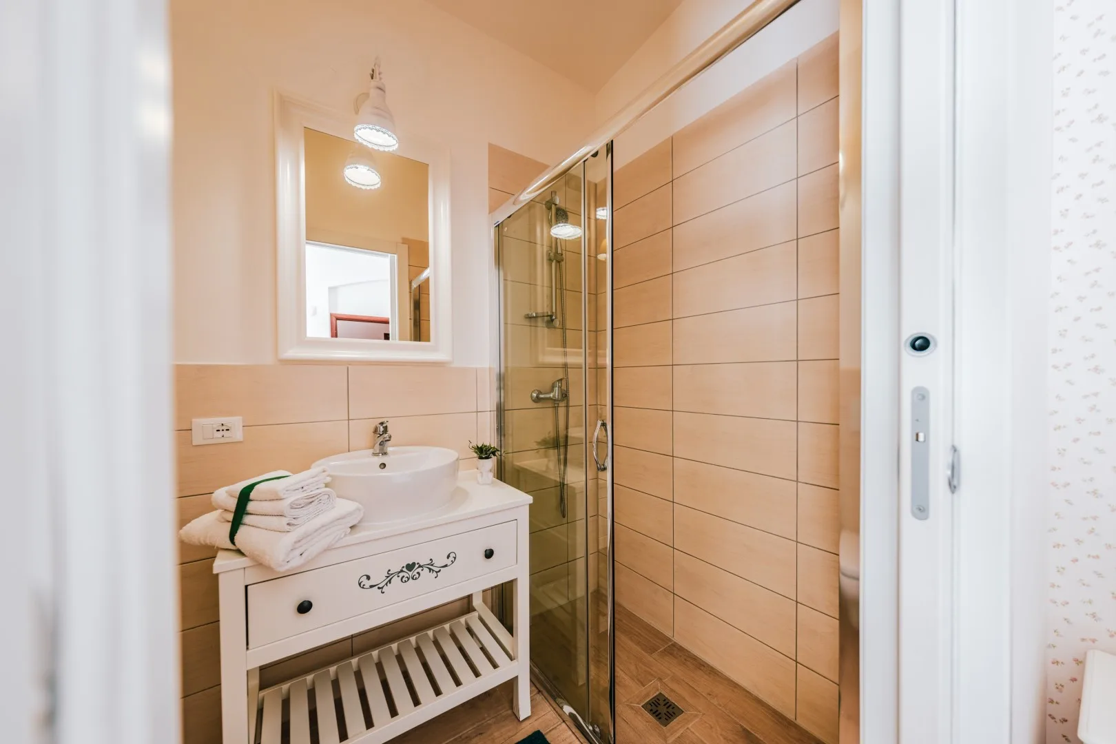 A bathroom with a sink vanity and a glass-enclosed shower.