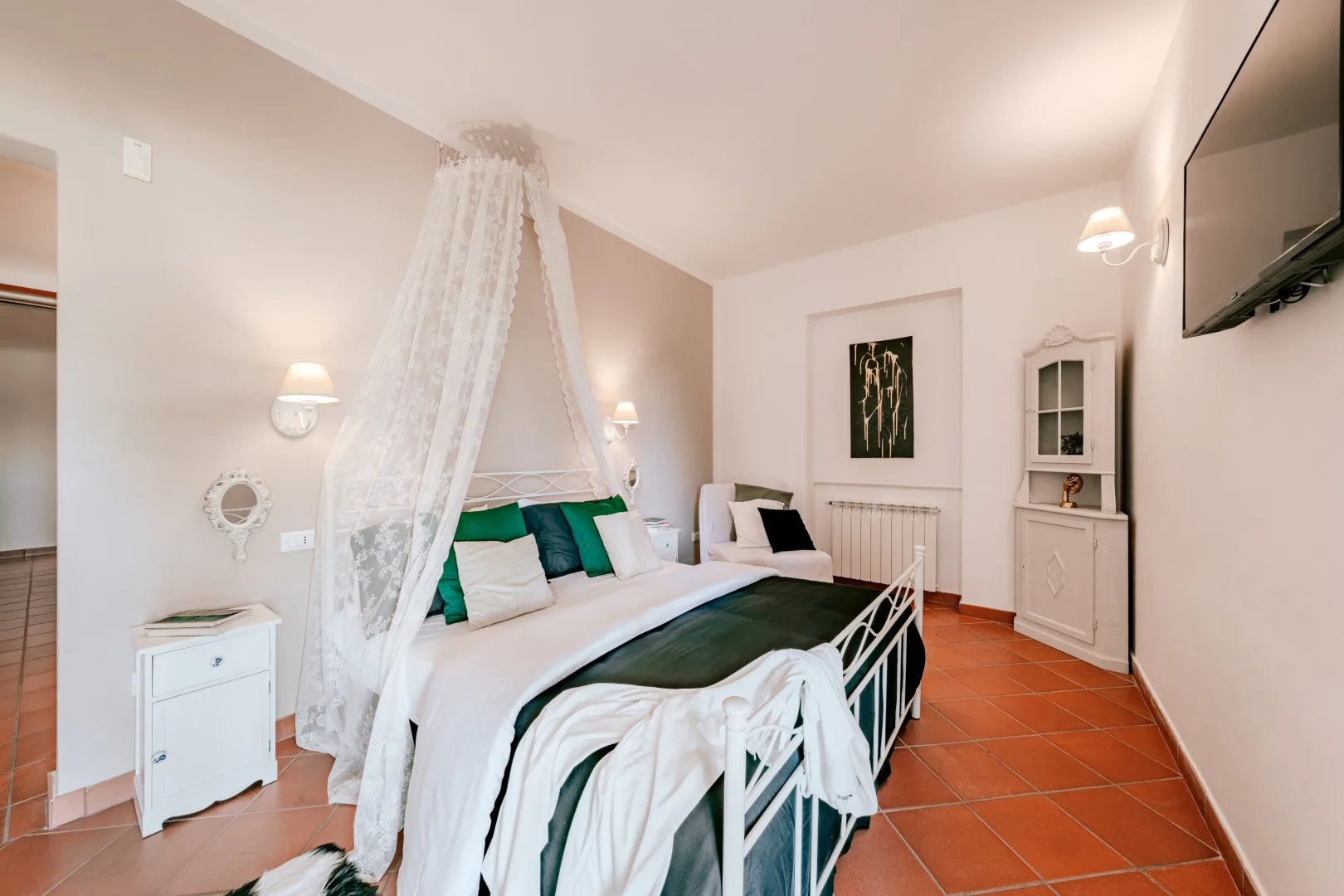 A bedroom with a canopied bed and white bedding.