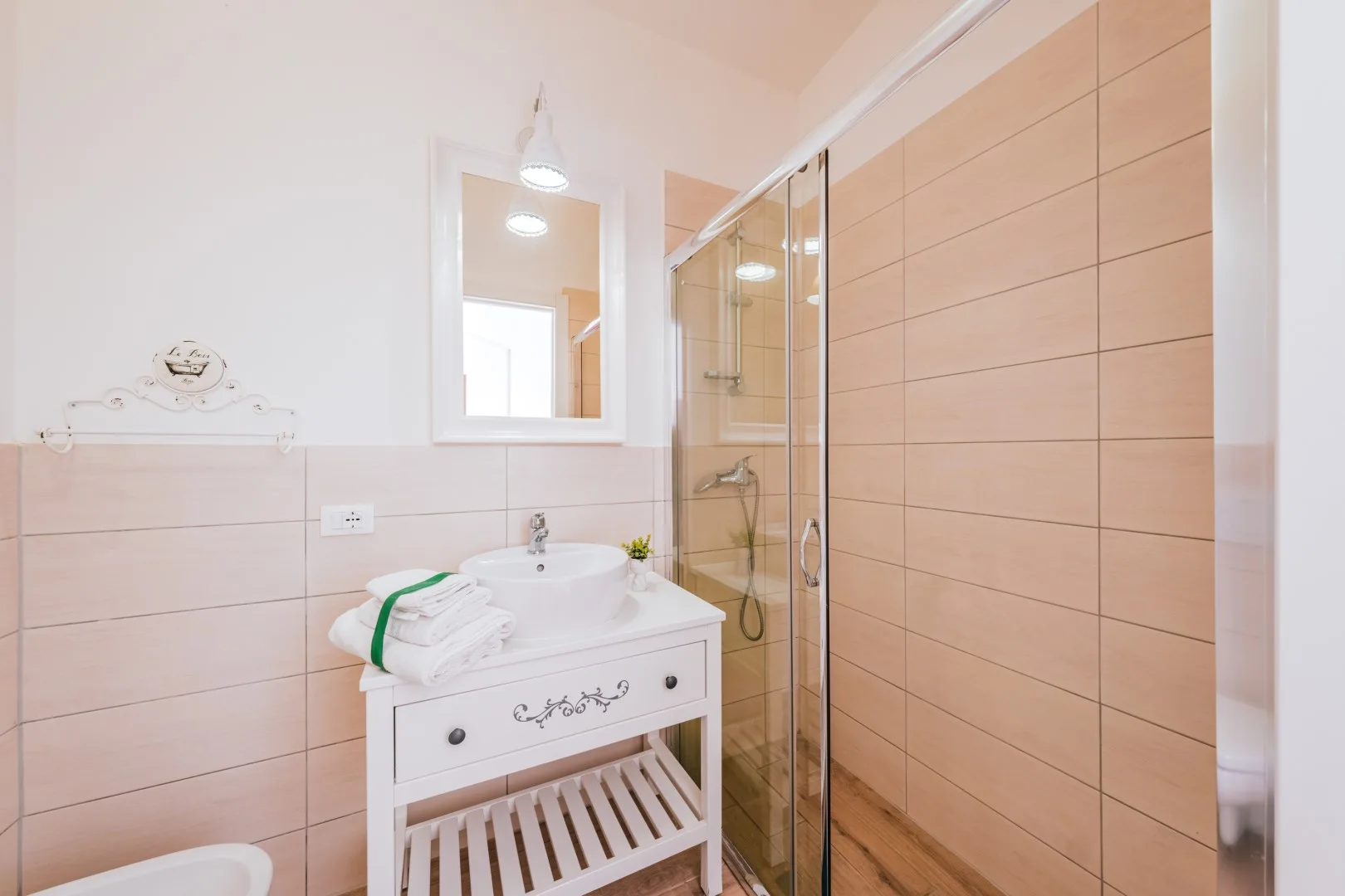 A bright bathroom with a white sink vanity and glass shower.